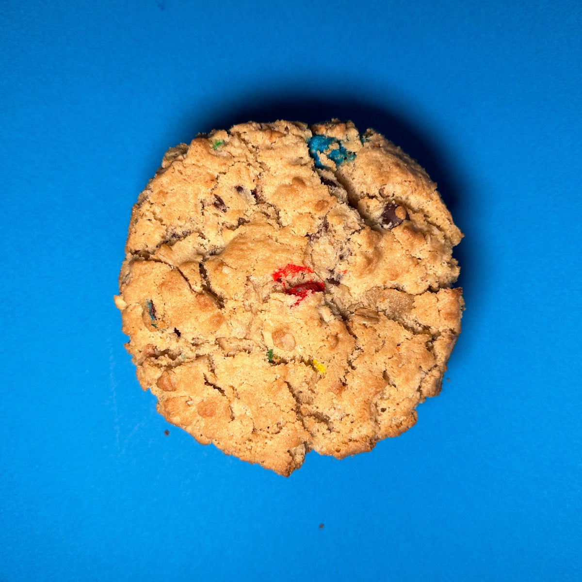 Mega Monster cookie with candy pieces, seen from above on a blue background
